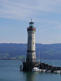 Lighthouse by sea against sky