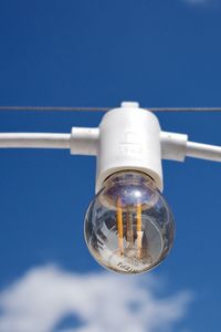 Low angle view of light bulb against blue sky