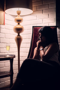 Midsection of woman sitting on table at home