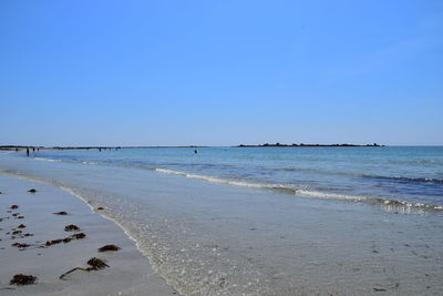 Scenic view of beach against clear blue sky