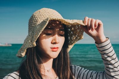 Close-up of young woman in hat against sea