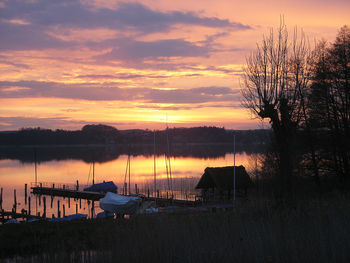 Silhouette sailboats moored on lake against sky during sunset