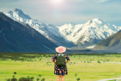 Rear view of person on snowcapped mountain against sky