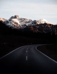 Empty road by mountains against sky