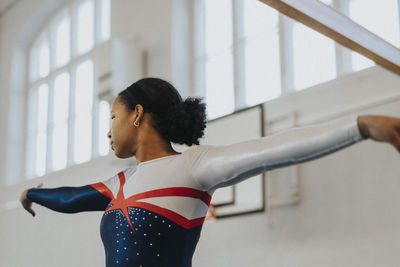 Dedicated female athlete with arm outstretched practicing exercise in gym