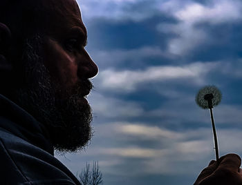 Close-up of a man with umbrella against cloudy sky