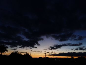 Low angle view of silhouette trees against dramatic sky