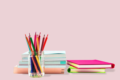 Stack of multi colored pencils on table against white background