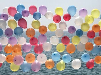 Multi colored balloons hanging against sea