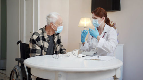Doctor wearing mask talking with patient in clinic
