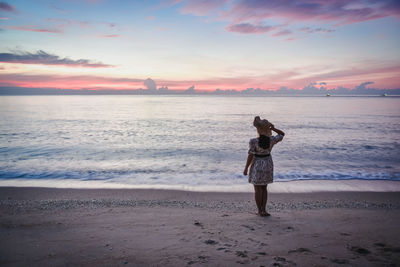 Rear view of man standing on beach during sunset