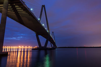 Low angle view of suspension bridge over river at night