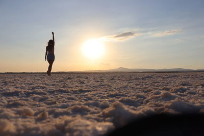 Woman standing on land against sky during sunset