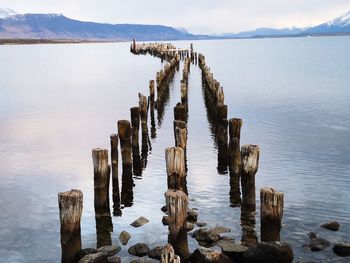 Wooden posts in sea against sky