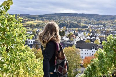 Rear view of woman looking at cityscape against mountain