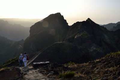 Rear view of friends walking on mountain during sunset