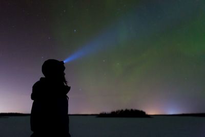 Silhouette woman standing against sky at night