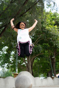 Full length of woman jumping against trees