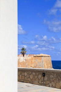 Built structure by sea against blue sky