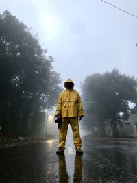 Full length of fire fighter standing on road during rain