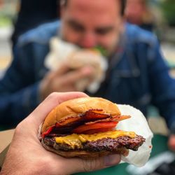 Cropped hand of man holding burger in restaurant