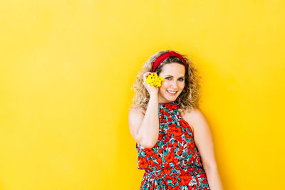 Portrait of a smiling young woman against yellow background
