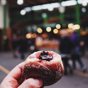 Cropped hand holding fresh donut on street