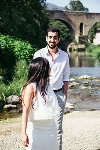 Couple looking at each other while walking against river