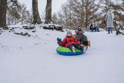 Cute caucasian boys having a ride on snow tubing in winter park