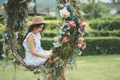 Side view of woman with pink flowers on field