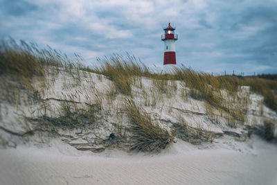 Lighthouse on snow covered land against sky