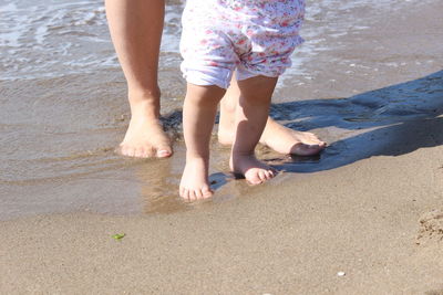 Low section of mother and daughter at beach