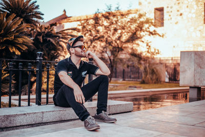 Woman sitting by tree in city