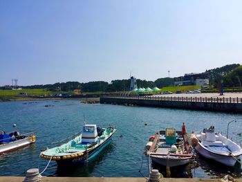 Boats moored in river against clear blue sky