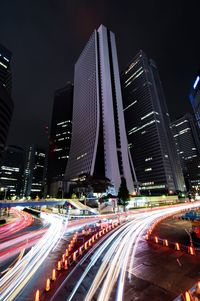 Light trails on city street by buildings at night