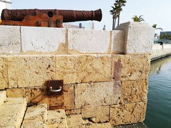 Close-up of weathered wall by sea against sky