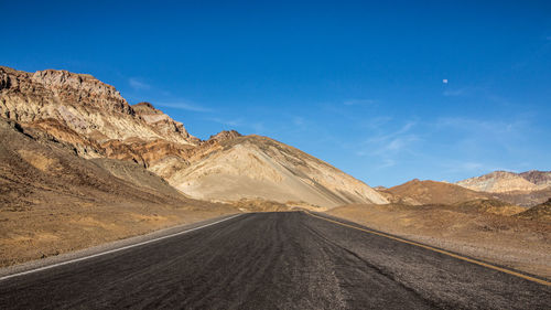 Road leading towards mountains against sky