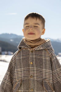 Portrait of little adorable boy with winter landscape in the background. cute smiling child