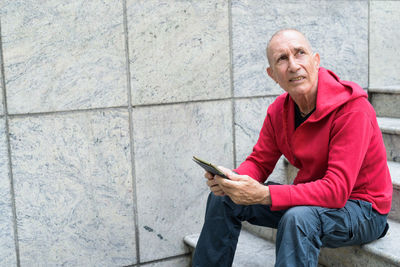 Portrait of man using mobile phone while sitting outdoors