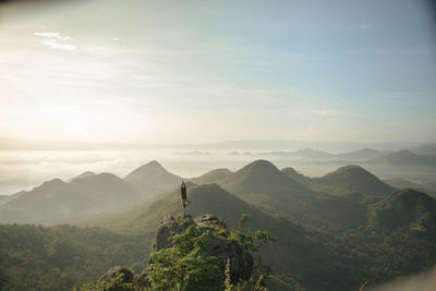 Person doing yoga on mountain against sky