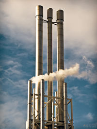 Low angle view of smoke stacks against sky