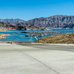 Scenic view of sea and mountains against clear blue sky