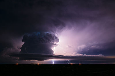 Lightning bolts illuminate a supercell thunderstorm in the night sky near earth, texas.