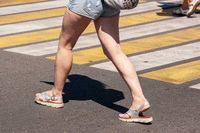 Low section of woman walking on road