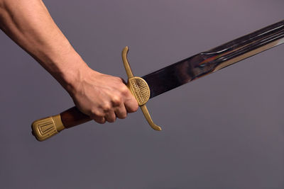 Close-up of hand holding metal against white background