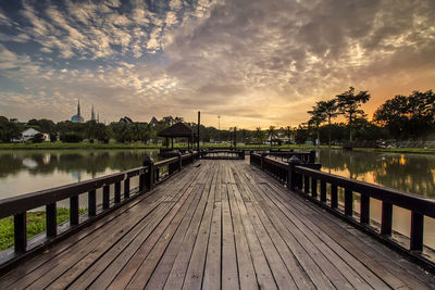 View of footpath by lake against sky during sunset