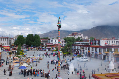 Group of people in front of buildings in city against sky