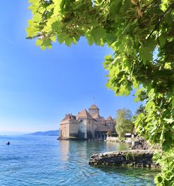 Buildings by sea against blue sky