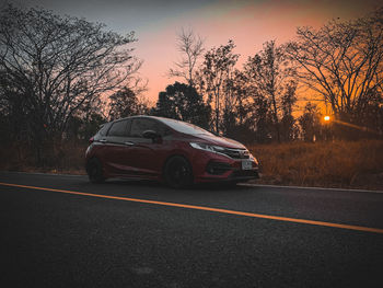 Car on road against sky at sunset