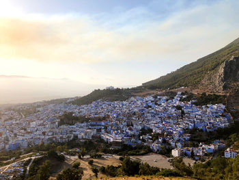 Aerial view of townscape by mountain against sky